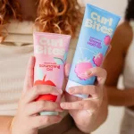 Kézben tartott rózsaszín Curl Bites Scrunching Gel és kék Strong Hold Gel hajformázó zselé tubusok.