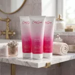 Három flakon Curly Secret Volume+ hajformázó zselé egy fürdőszobai márványpulton elhelyezve.