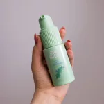 Kézben tartott, világoszöld Curl Bites Volumizing Dry Shampoo szárazsampon pumpás adagolófejjel.