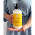 Kézben tartott pumpás Soivre Curly Method Co-Wash Mask flakon sárga címkével, világoskék farmerruha előtt.