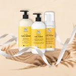 Három darab sárga címkés Soivre Cosmetics Curly Method hajápoló termék egy fa talpazaton, fehér szalaggal körülvéve.