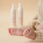 Kisbaba lábai kötött ruhában, a háttérben a NAYEEL My First habsampon és hajpermet flakonjai