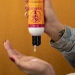 Fehér színű Jessicurl Spiralicious formázó gél adagolása flakonból tenyérbe a textúra bemutatására.