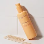 Rizos Curls 6-in-1 hajformázó krém fésüvel, fehér csemps háttérrel.