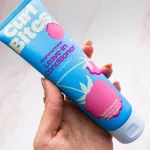 Kézben tartott kék Curl Bites Weightless Protein Leave-In Conditioner tubus rózsaszín málnás mintával.