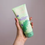 Curl Bites Rosemary mélytisztító sampon világoszöld tubusban, rozmaring mintával kézben tartva.