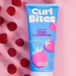 Curl Bites Multi Protein Deep Conditioner kék tubusos mélykondicionáló málnákkal rózsaszín háttér előtt.