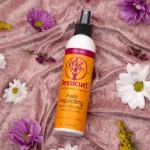 Jessicurl Awe Inspiraling hajfelfrissítő spray flakonja virágokkal díszített rózsaszín bársonyon.